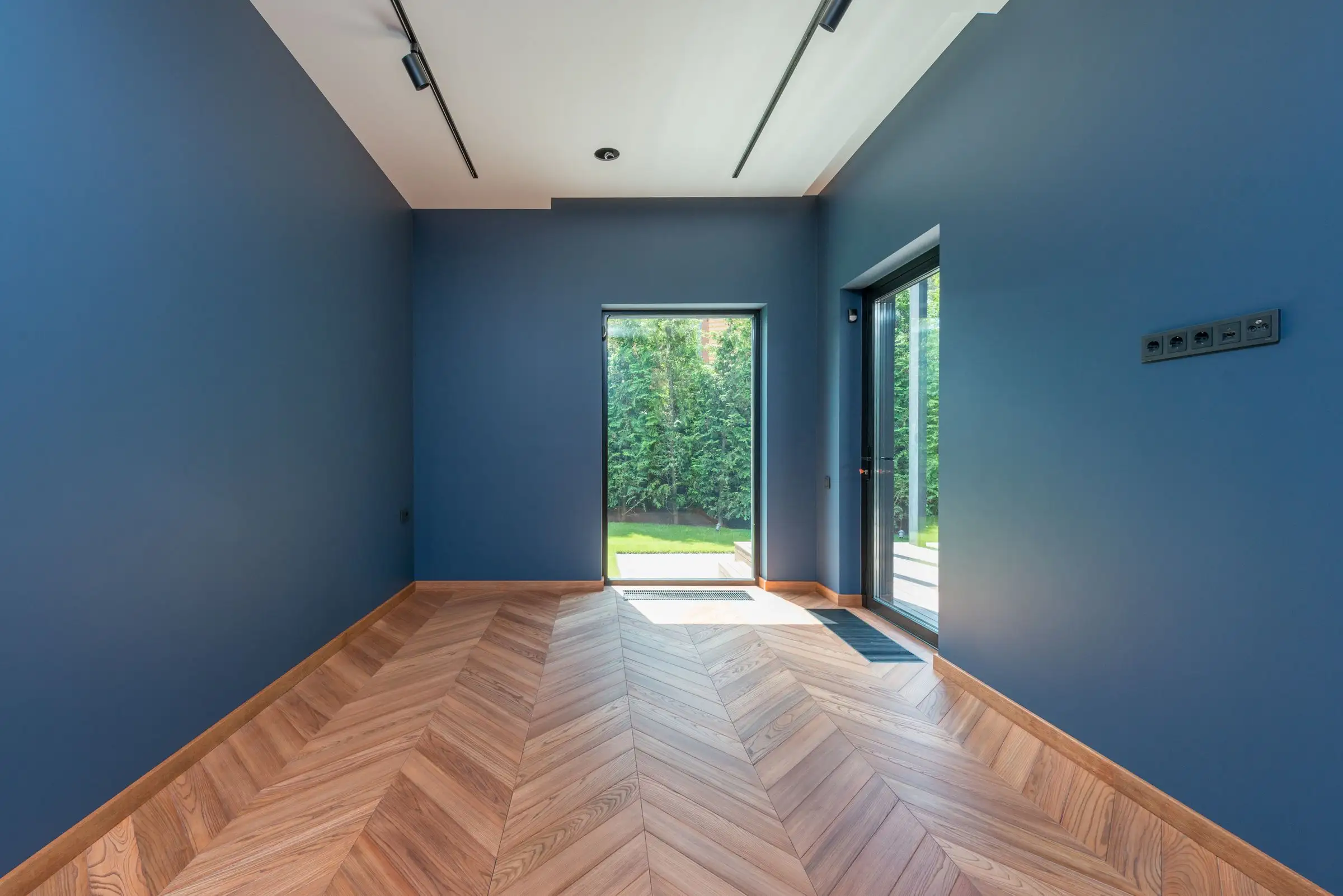 Chambre aux murs bleus et parquet en chevrons, porte-fenêtre