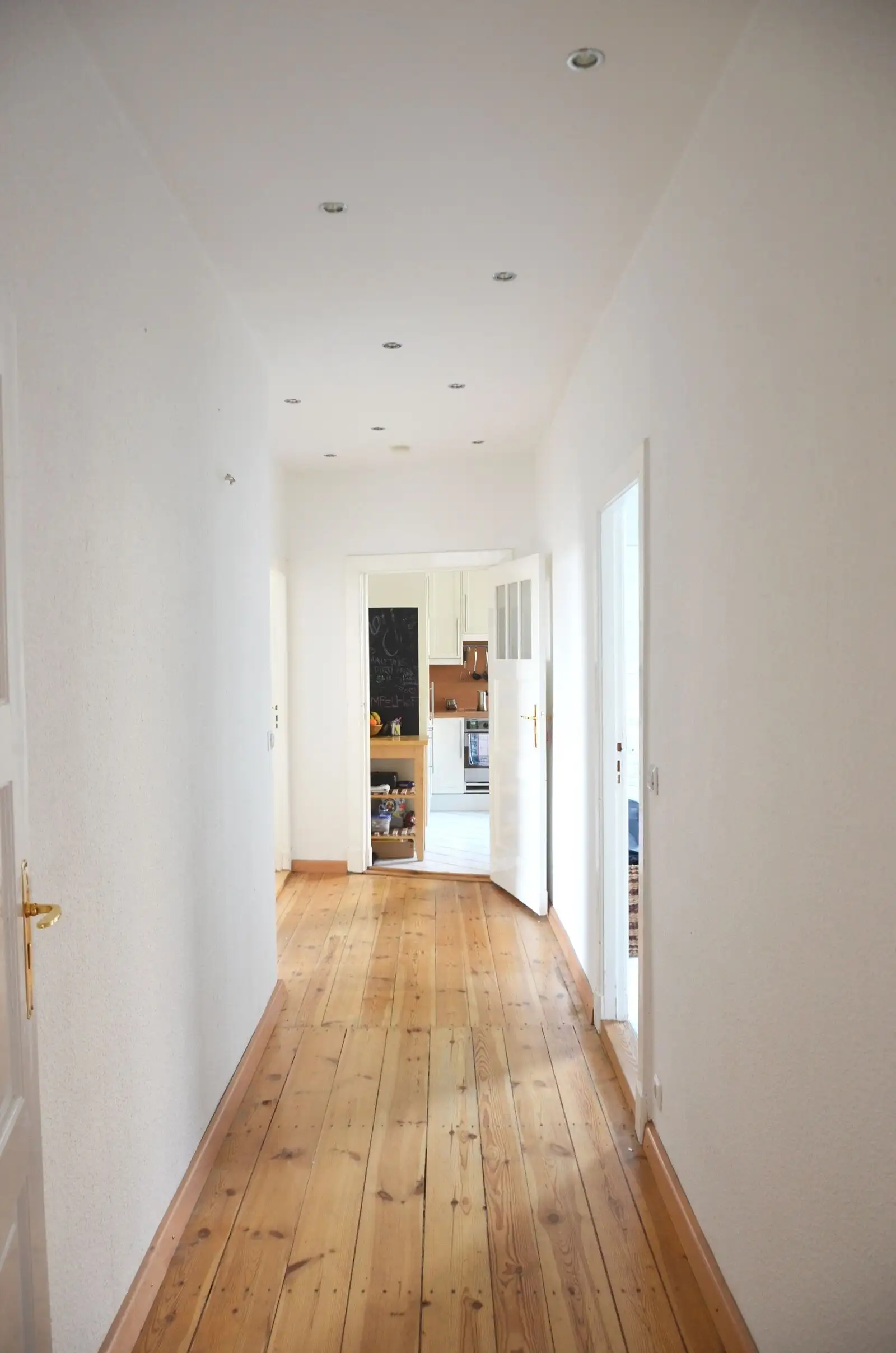 Couloir d’appartement repeint, parquet et portes blanches