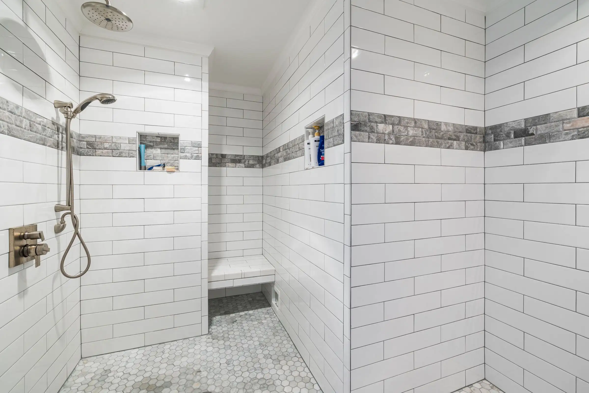 Douche carrelée en blanc avec banc maçonné et frise