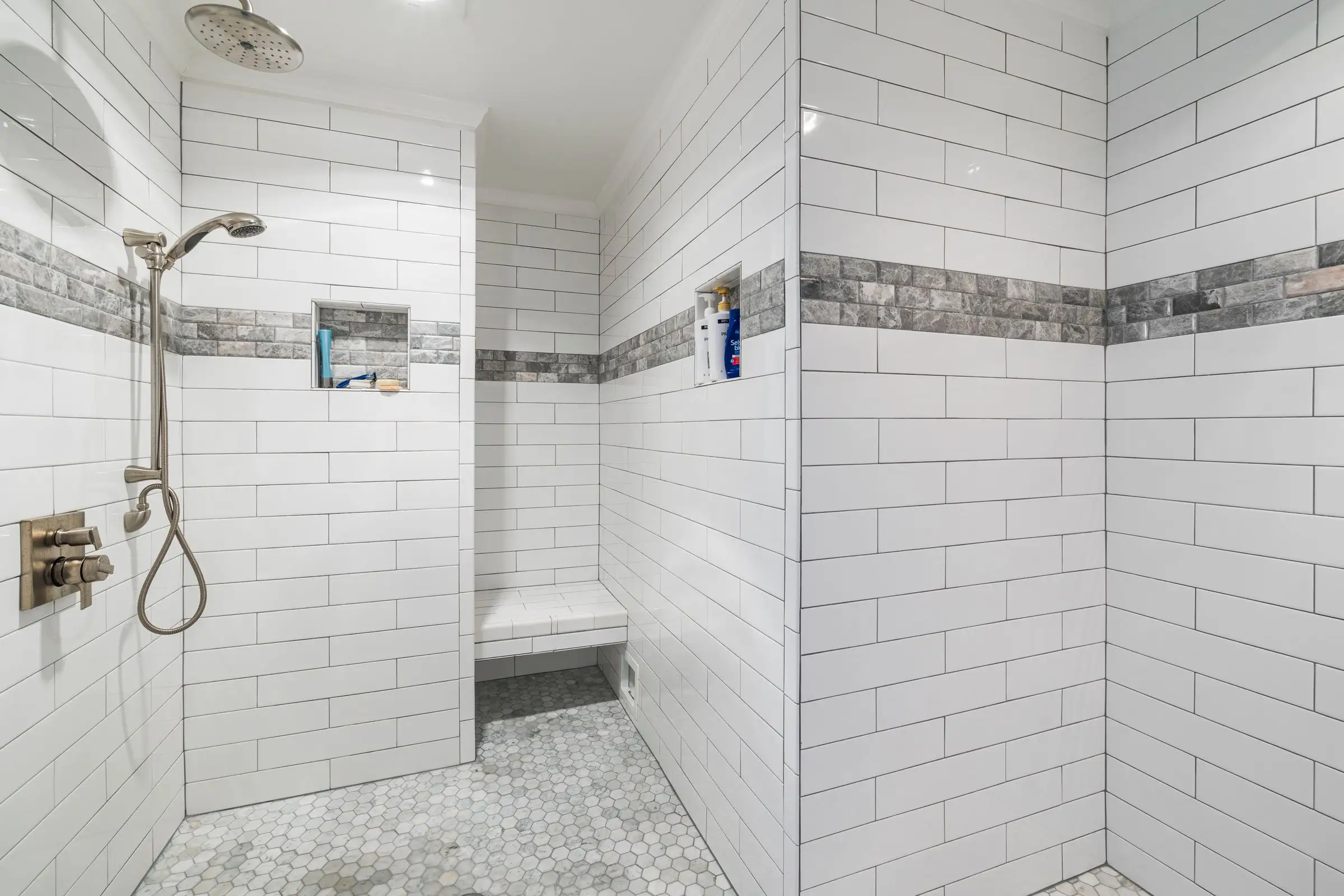 White-tiled shower with a built-in bench and a border