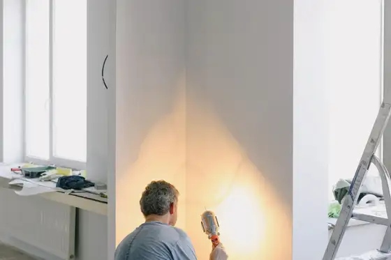 Électricien de dos dans une pièce d’un appartement ancien