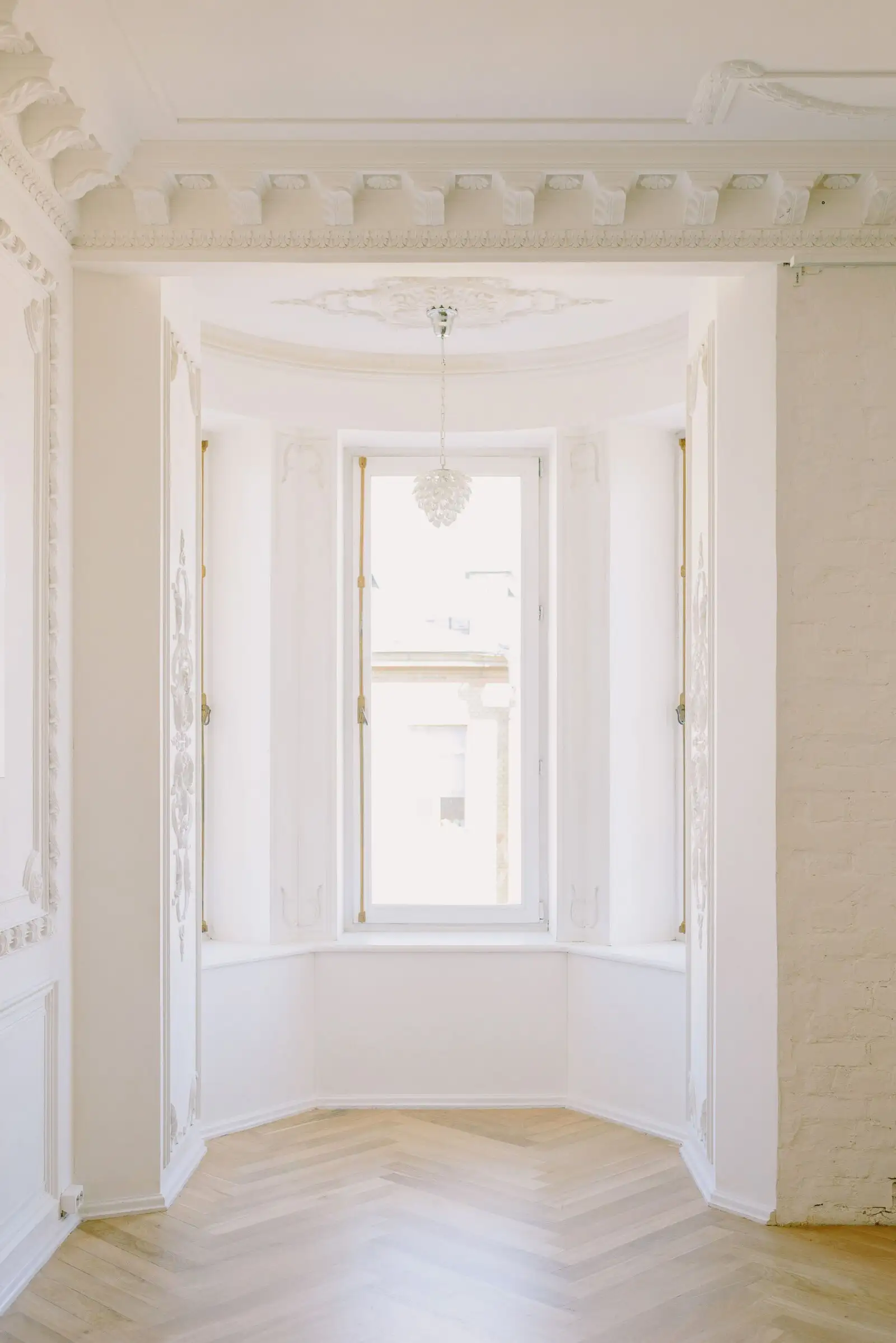 Room with white cornices, a bay window and pale parquet
